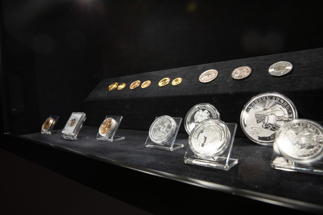 Ausgestellte Edelmetalle als Münzen und Barren in einer Glasvitrine. Diese Edelmetalle erhalten Sie auch in unserem Goldgeschäft in Görlitz.